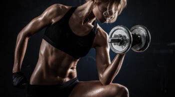 Strong woman lifting a dumbbell in a dark gym setting