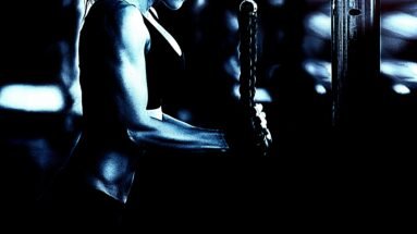 Close-up of a woman performing tricep exercises with a cable machine in a dark gym.