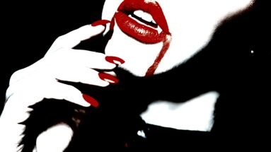 Close-up of a woman's red lips and nails with a hint of fangs, highlighting vampire goth velvet attire.