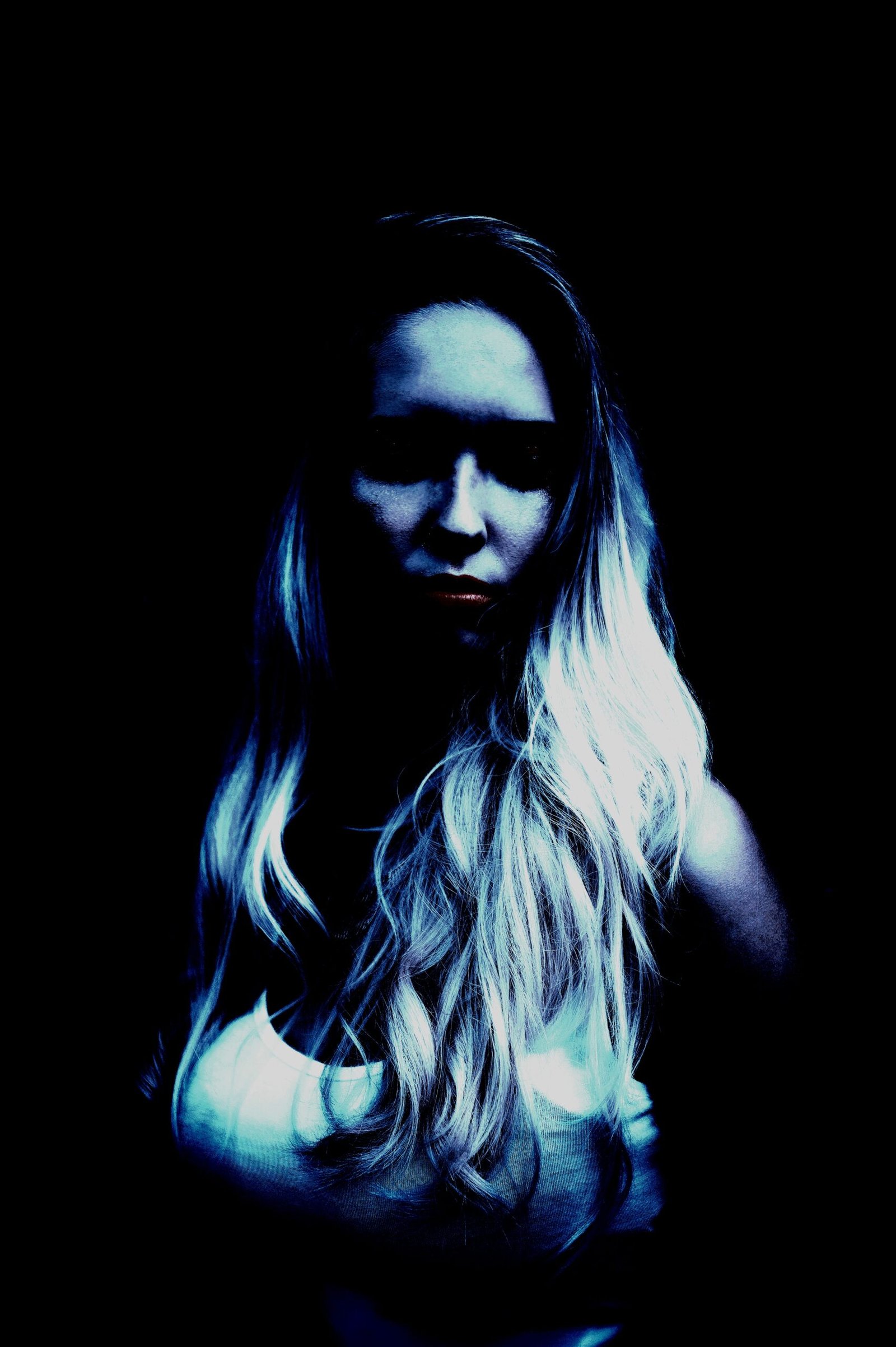 Moody portrait of a blonde woman in dark lighting, with a mysterious and intense expression. 