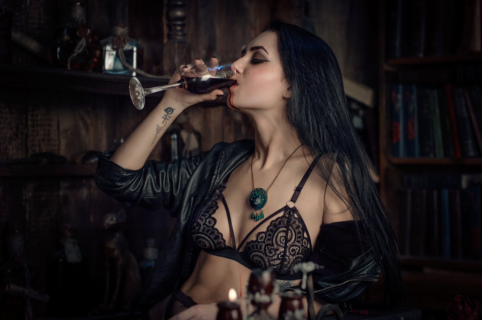 A woman in black lace lingerie drinking from a wine glass filled with blood, exuding a seductive, modern vampire vibe.