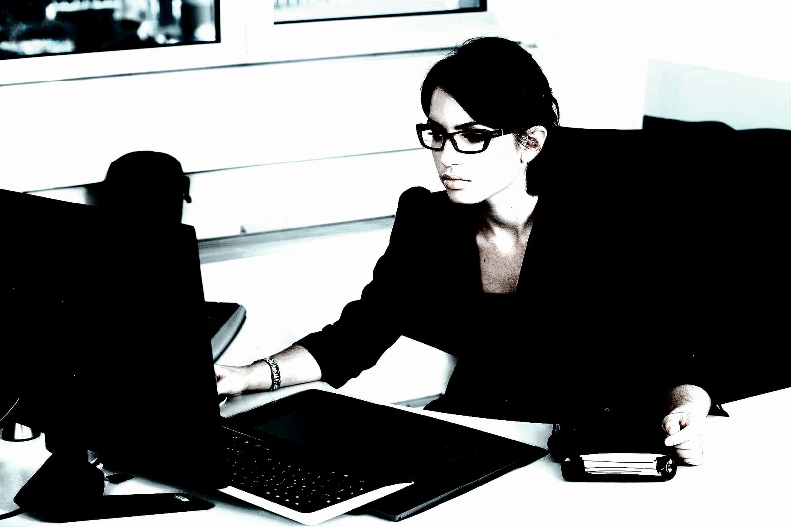 Woman in a secretary outfit sitting on a desk, wearing fishnet stockings and high heels.