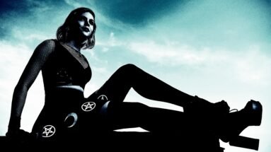A woman in a gothic outfit sitting on a rooftop, wearing black stockings with pentagram symbols, under a cloudy sky.