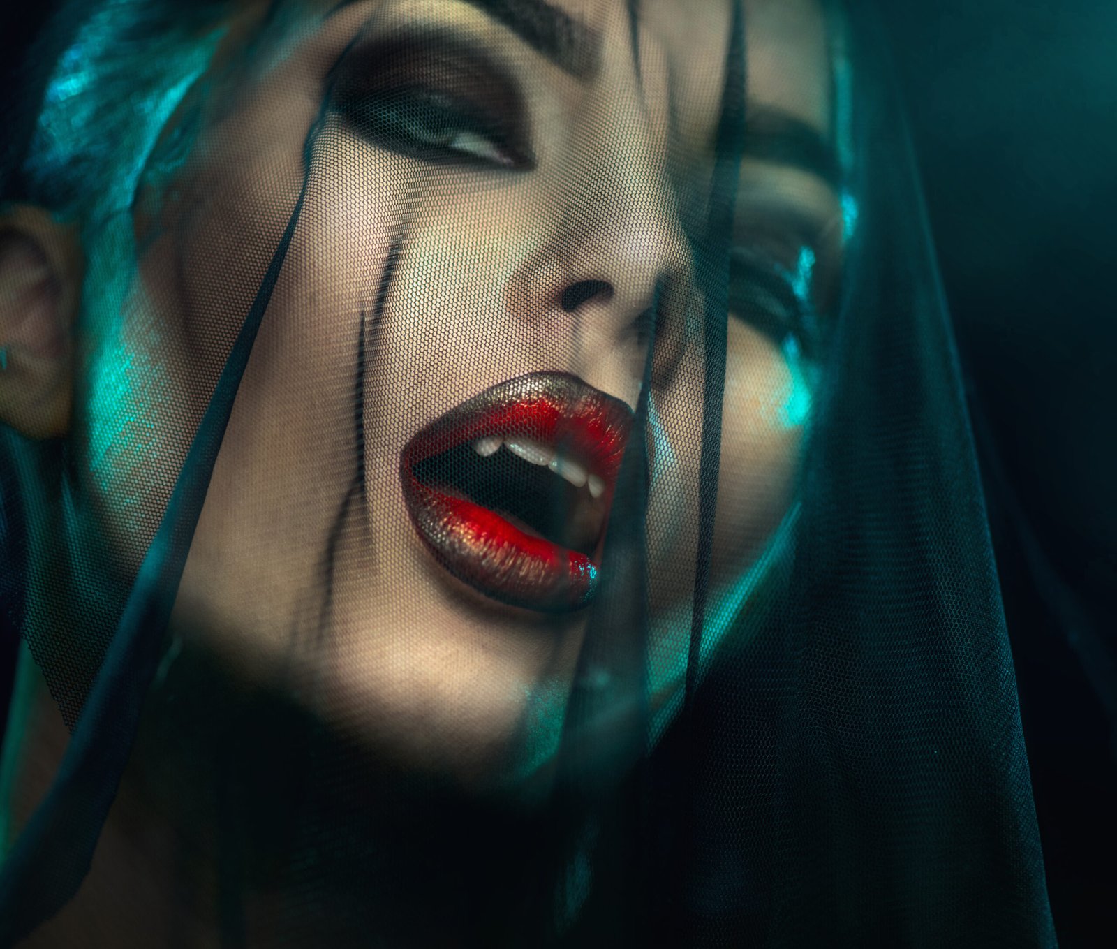 Woman with fangs and red lips behind a veil, evoking a mysterious and seductive vampire vibe.