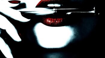 Woman's lips with red lipstick holding a pen horizontally.