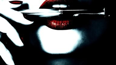 Woman's lips with red lipstick holding a pen horizontally.