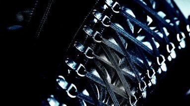 Close-up of the intricate lacing and metal hooks on a black corset, highlighting the detailed craftsmanship.
