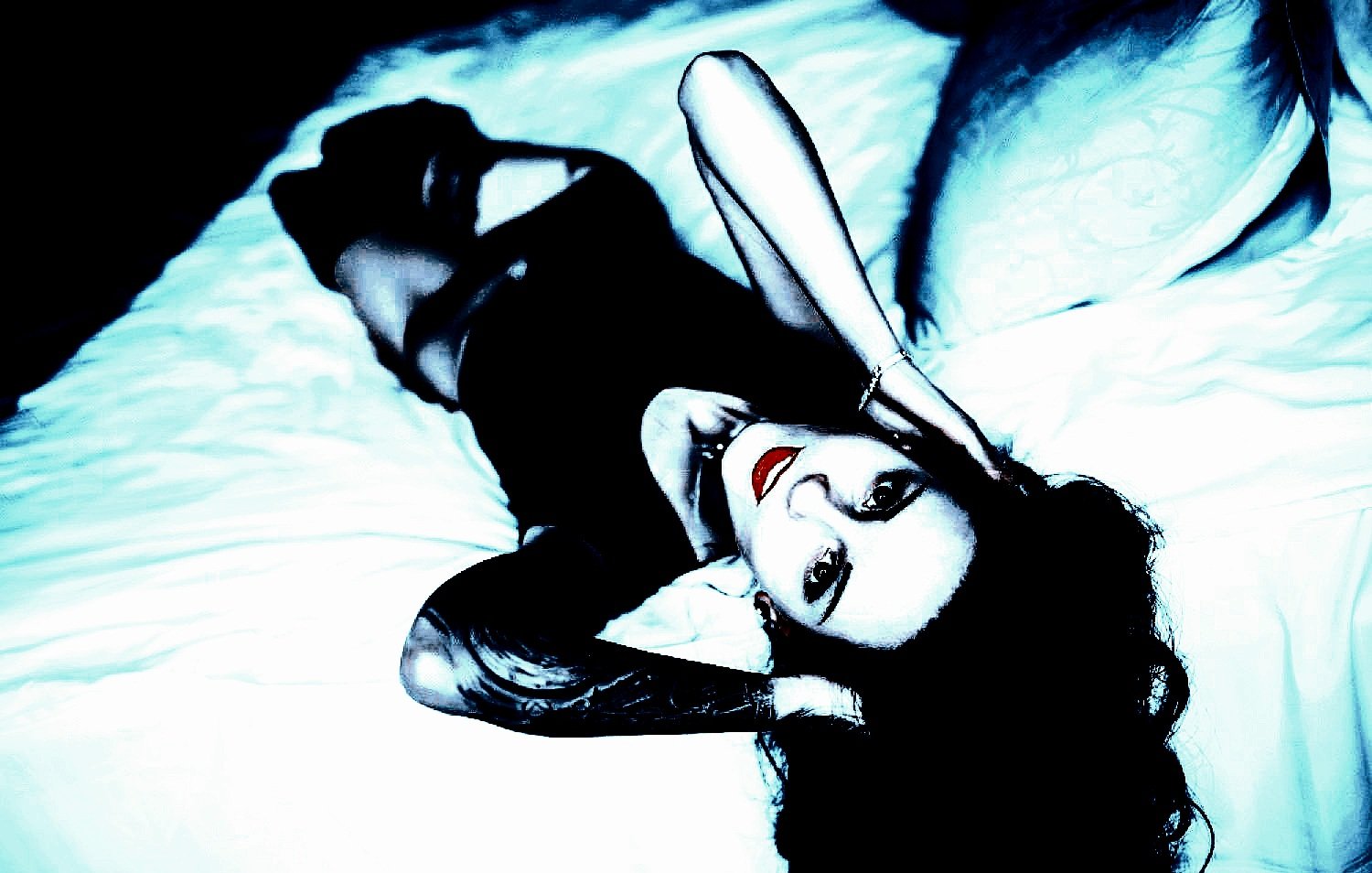 Sexy goth girl with tattoos in lingerie, lying on a bed.