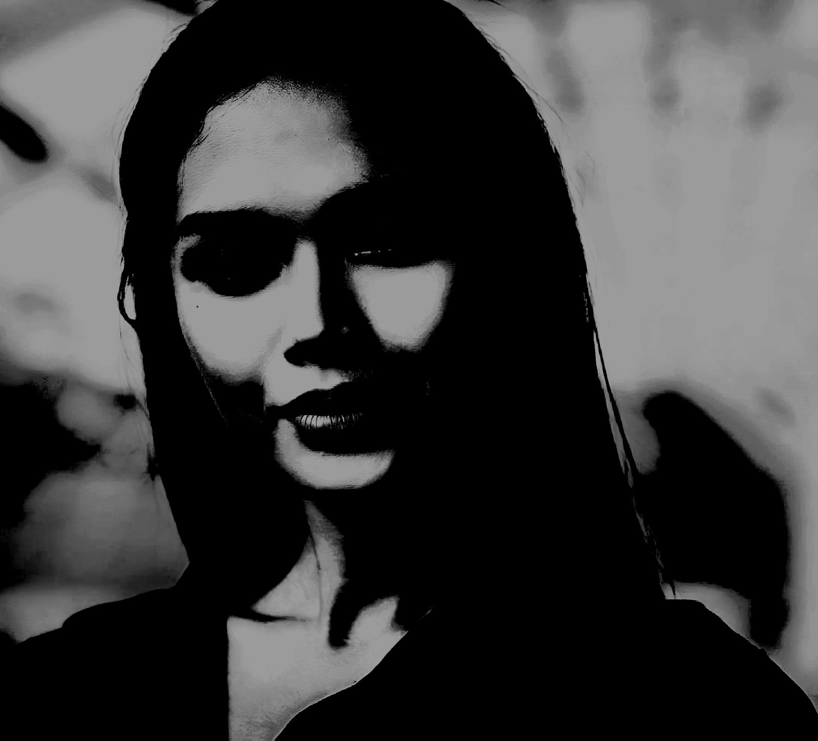 Black-and-white close-up of a woman’s face, her features highlighted by shadows, creating an air of mystery and seduction.