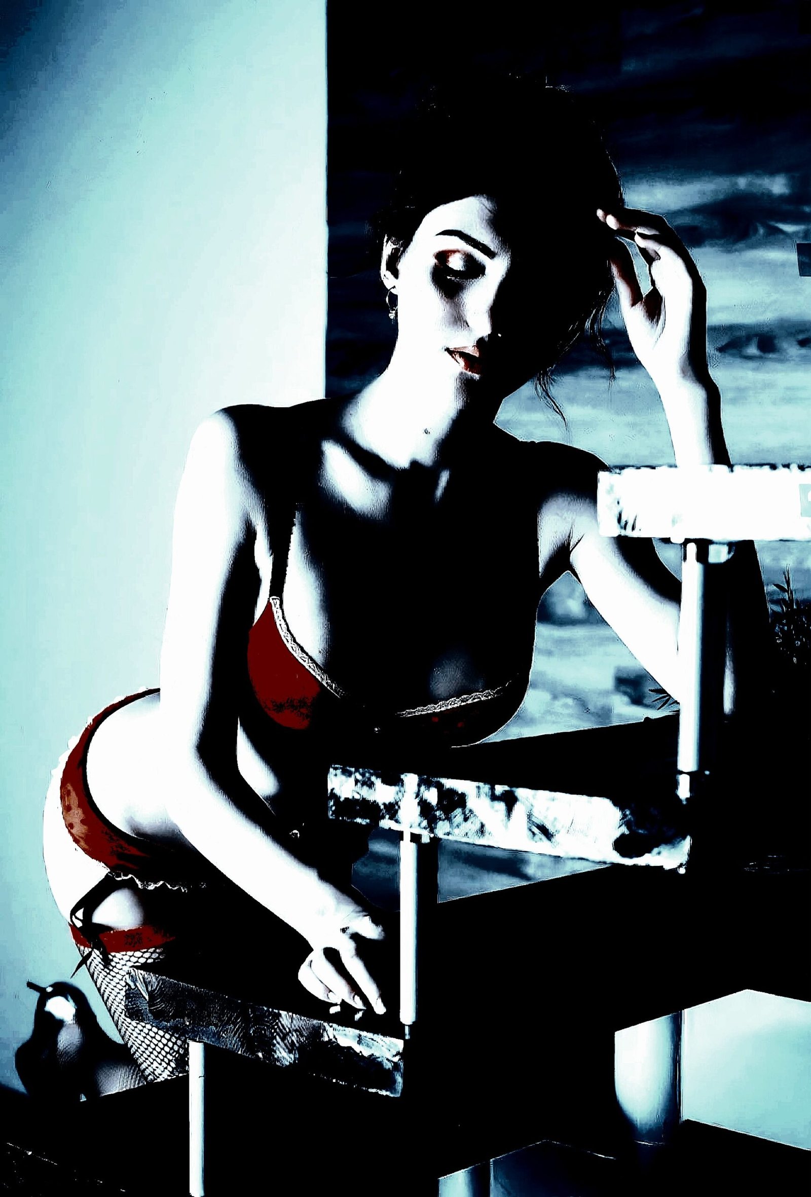 A woman in red lingerie, posed thoughtfully on a stairway, the lighting casting shadows across her face.
