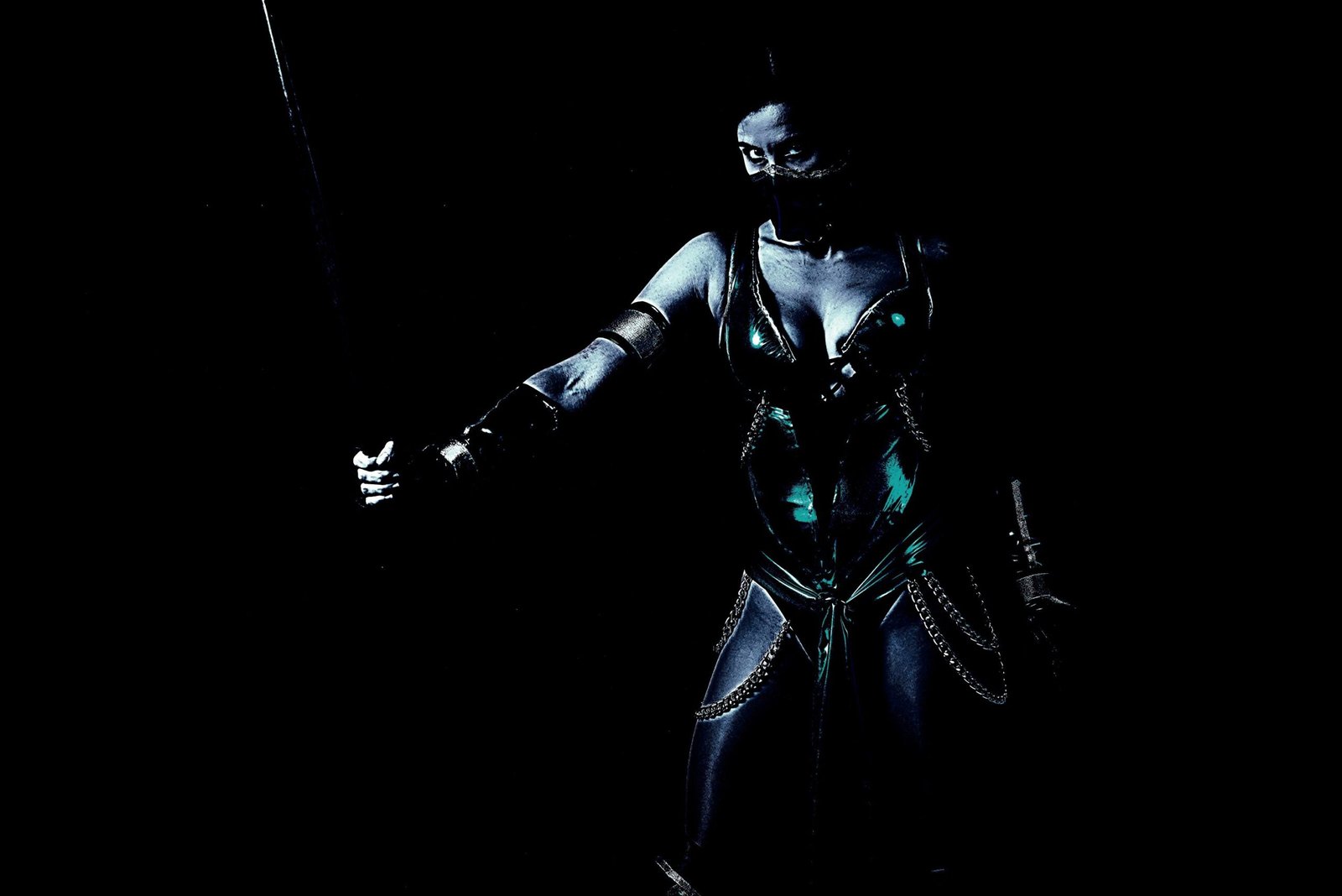 Cosplayer dressed as a dark, mysterious character from Mortal Kombat, wielding a staff and exuding a powerful presence in low lighting.