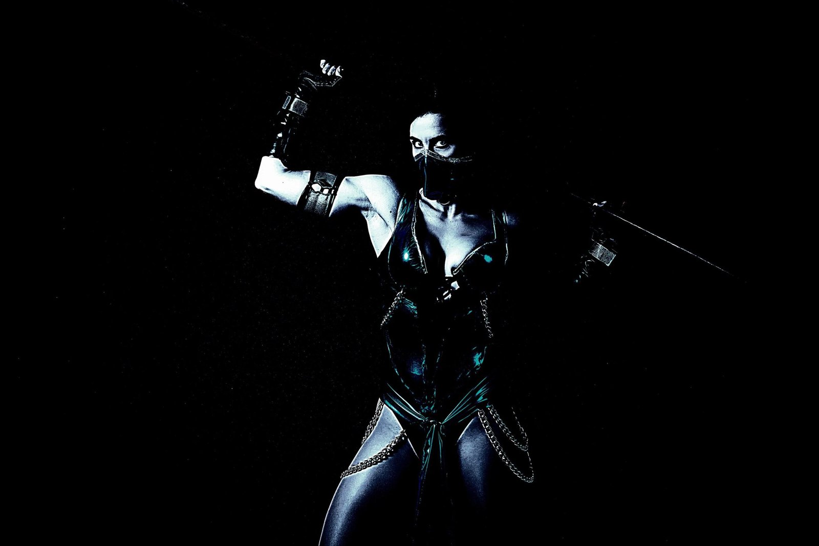 Close-up of a female Mortal Kombat character cosplay, holding a weapon with intense expression, capturing the essence of strength and mystery.