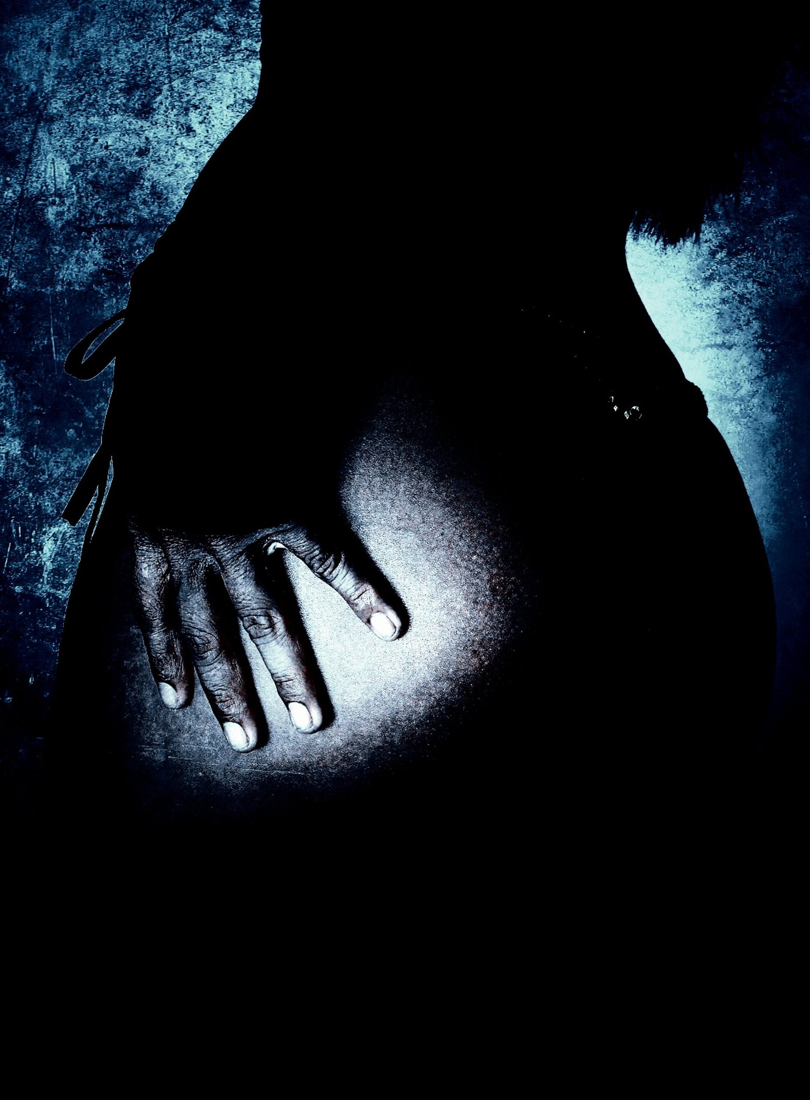 Close-up of a woman's hand resting on her hip, accentuating muscle definition and body composition in a dark, moody environment. 