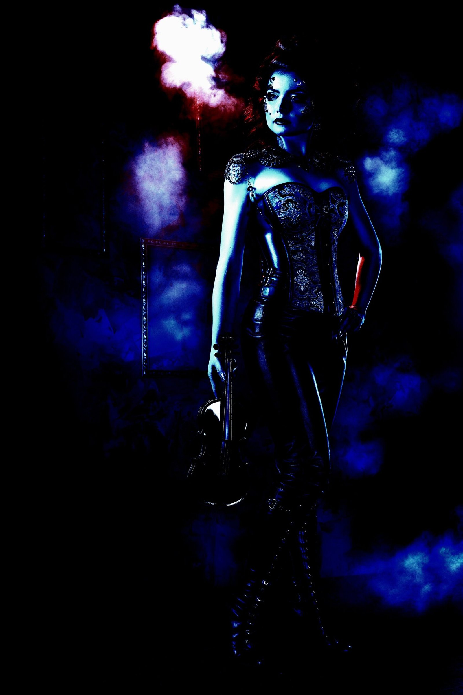Gothic woman in a Victorian-inspired corset and tight leather pants, standing confidently with a violin under eerie blue and red lighting, surrounded by smoke.