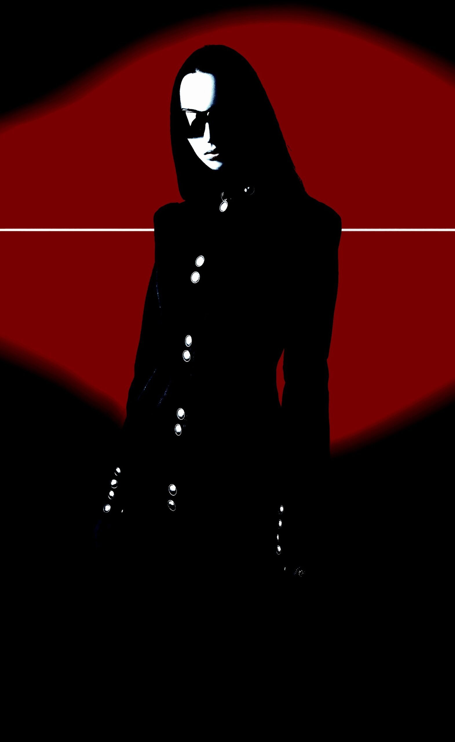 A woman dressed in all black, her face partially obscured by dark sunglasses, standing against a red and black abstract background, exuding a goth and futuristic atmosphere.