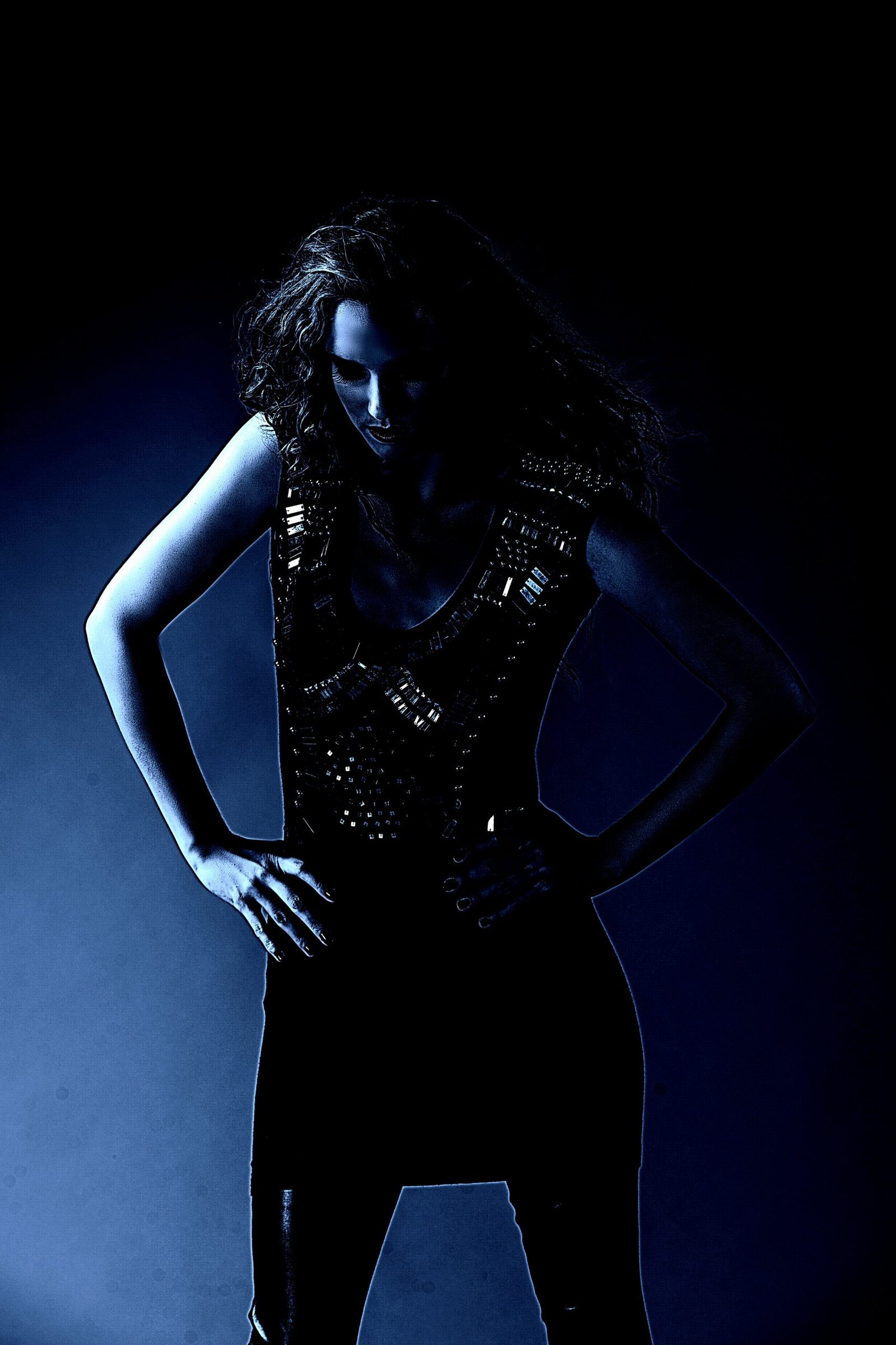 Confident woman in a metallic corset with spiked short hair, embodying futuristic and cyberpunk-inspired gothic fashion in a dark background.