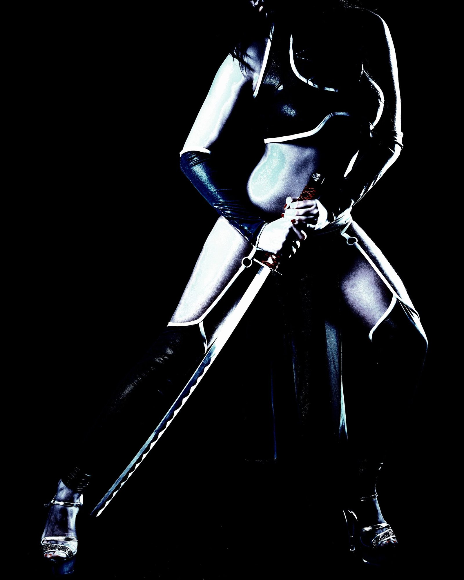 Powerful cosplay of a futuristic warrior wielding a sword, dressed in a revealing, metallic black costume against a dark backdrop. 