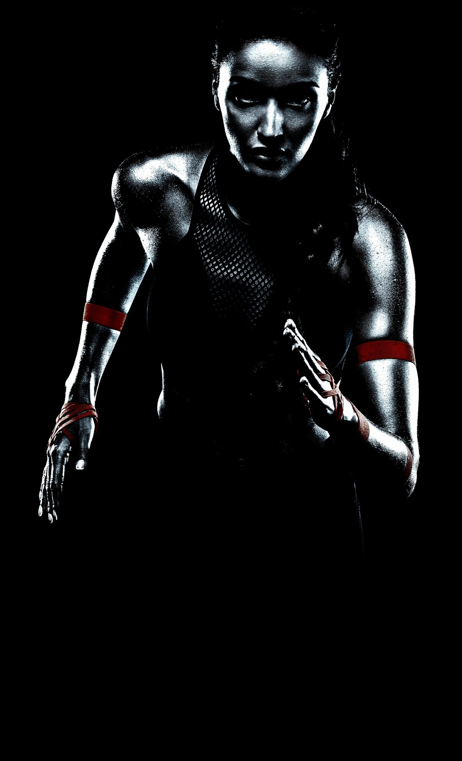 Athlete in mid-run, highlighting intense focus and strength, with muscles accentuated by low lighting, ready for action.