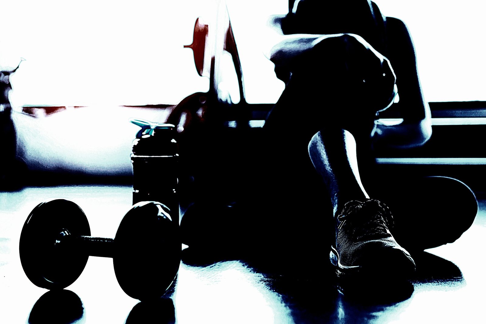 Silhouette of a person resting after a workout, with dumbbells and water bottle on the floor, capturing the calm after the intensity of exercise. 