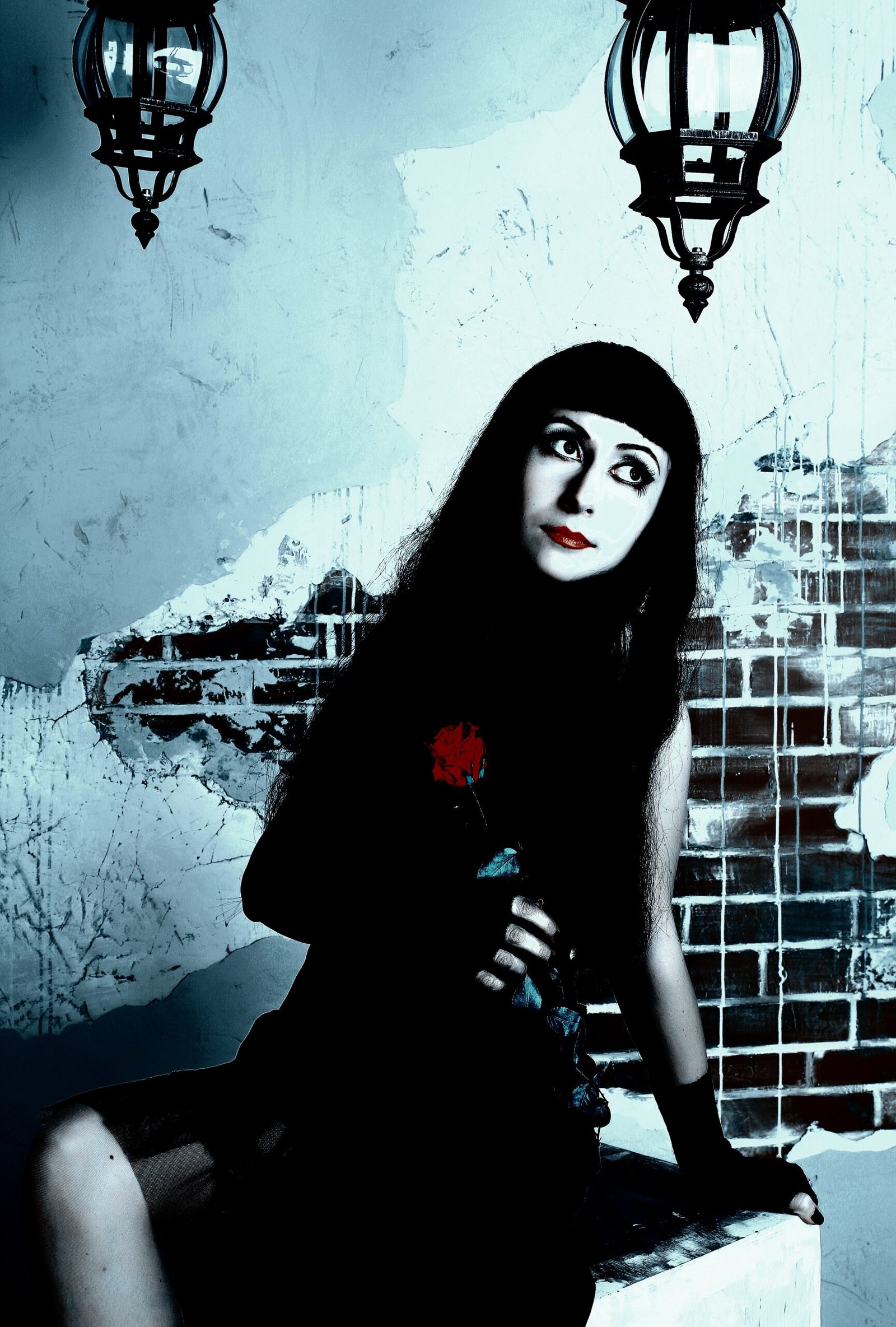 Woman in vintage gothic attire holding a red rose, sitting in front of a crumbling brick wall, with a haunting, melancholic expression.