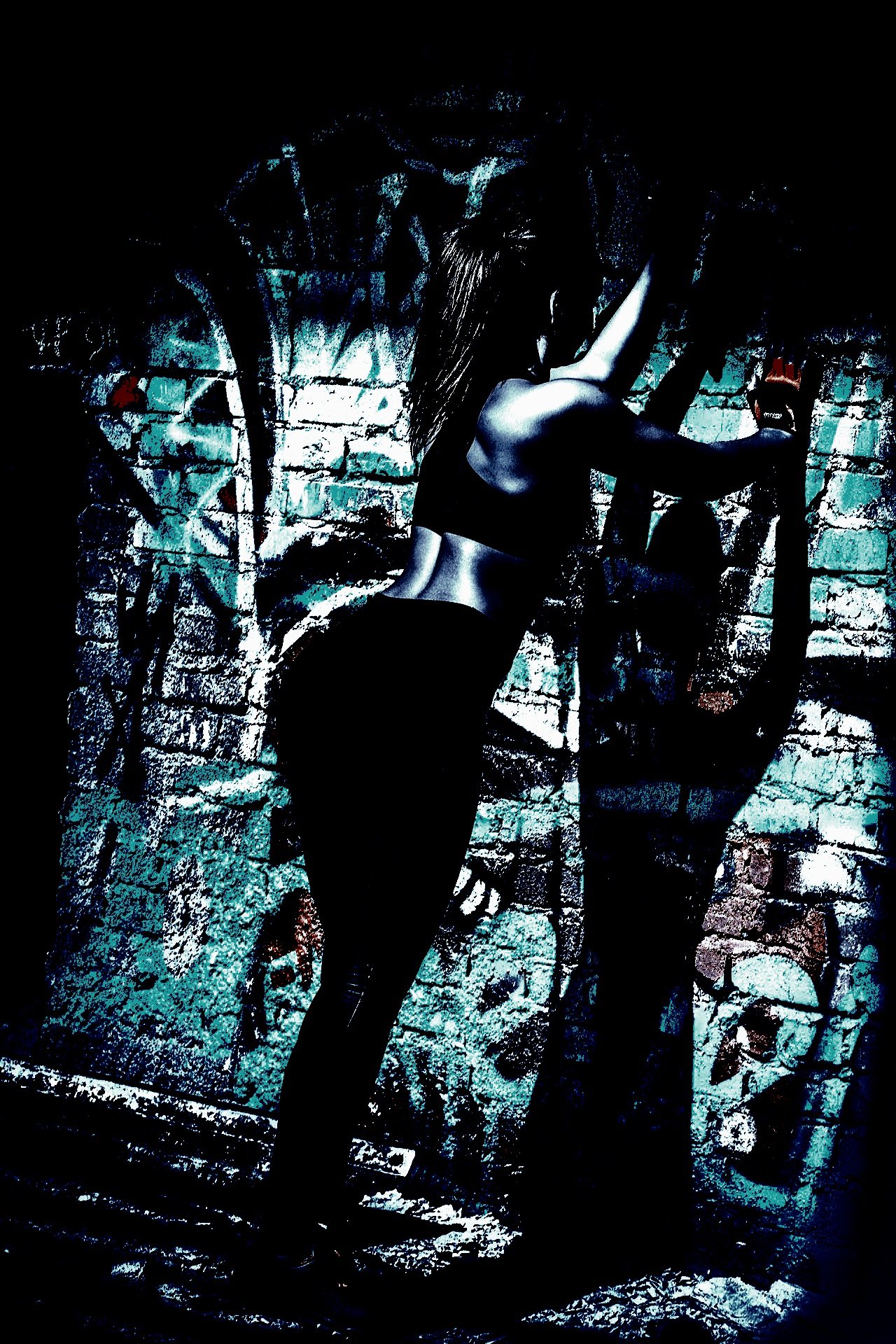 A woman stretching against a graffiti-covered brick wall, dressed in a dark sports outfit, illuminated in high-contrast lighting for an urban, gritty vibe.