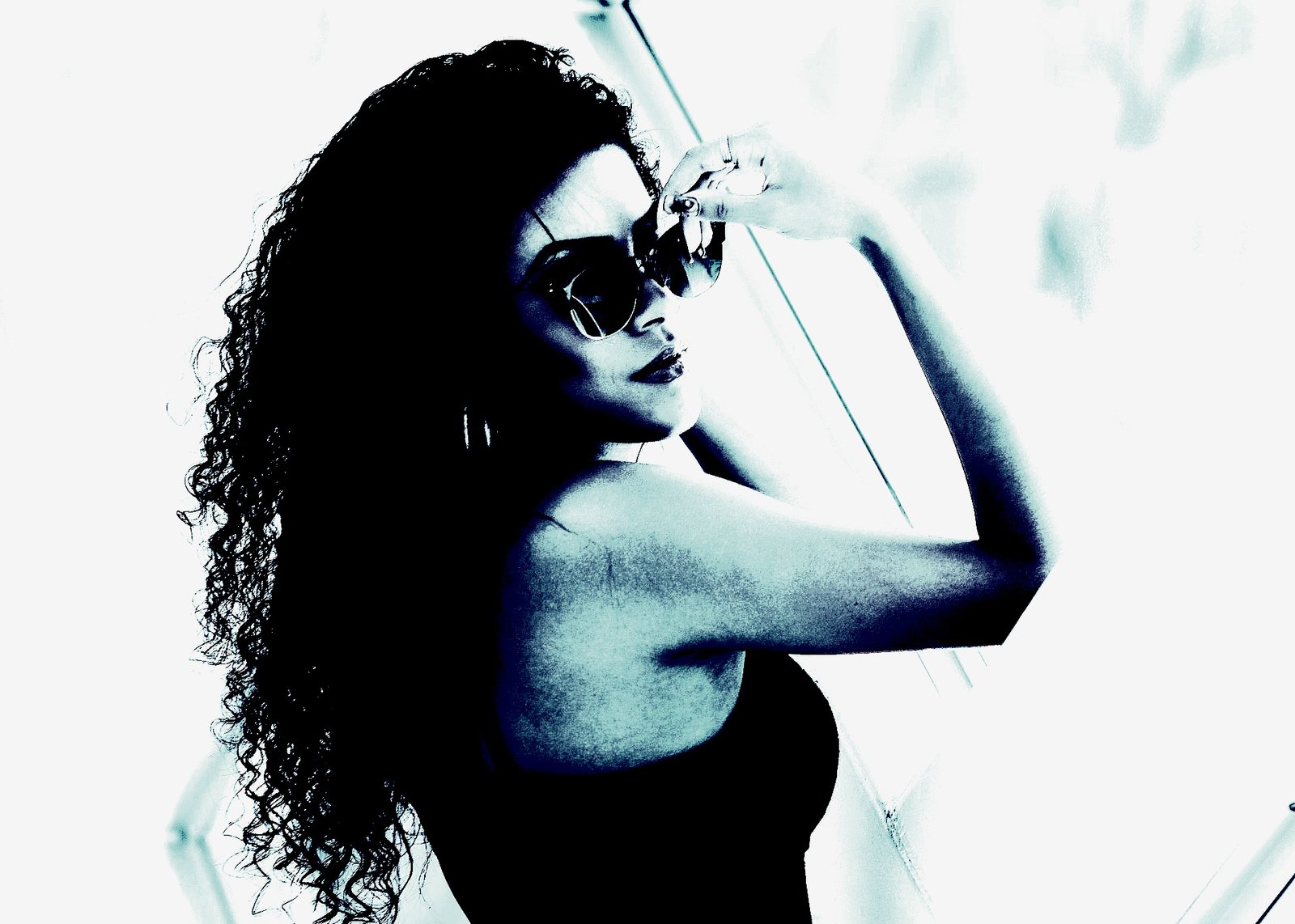 Woman applying red lipstick while wearing large black sunglasses, with a towel wrapped around her head.