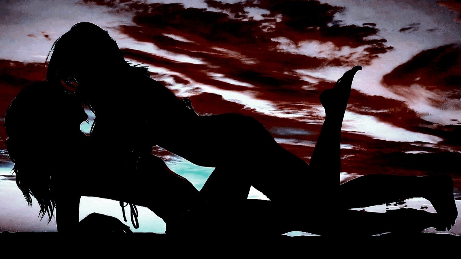 Silhouette of two people in an intimate pose against a dramatic sky with dark, red clouds, creating a powerful, emotional scene.