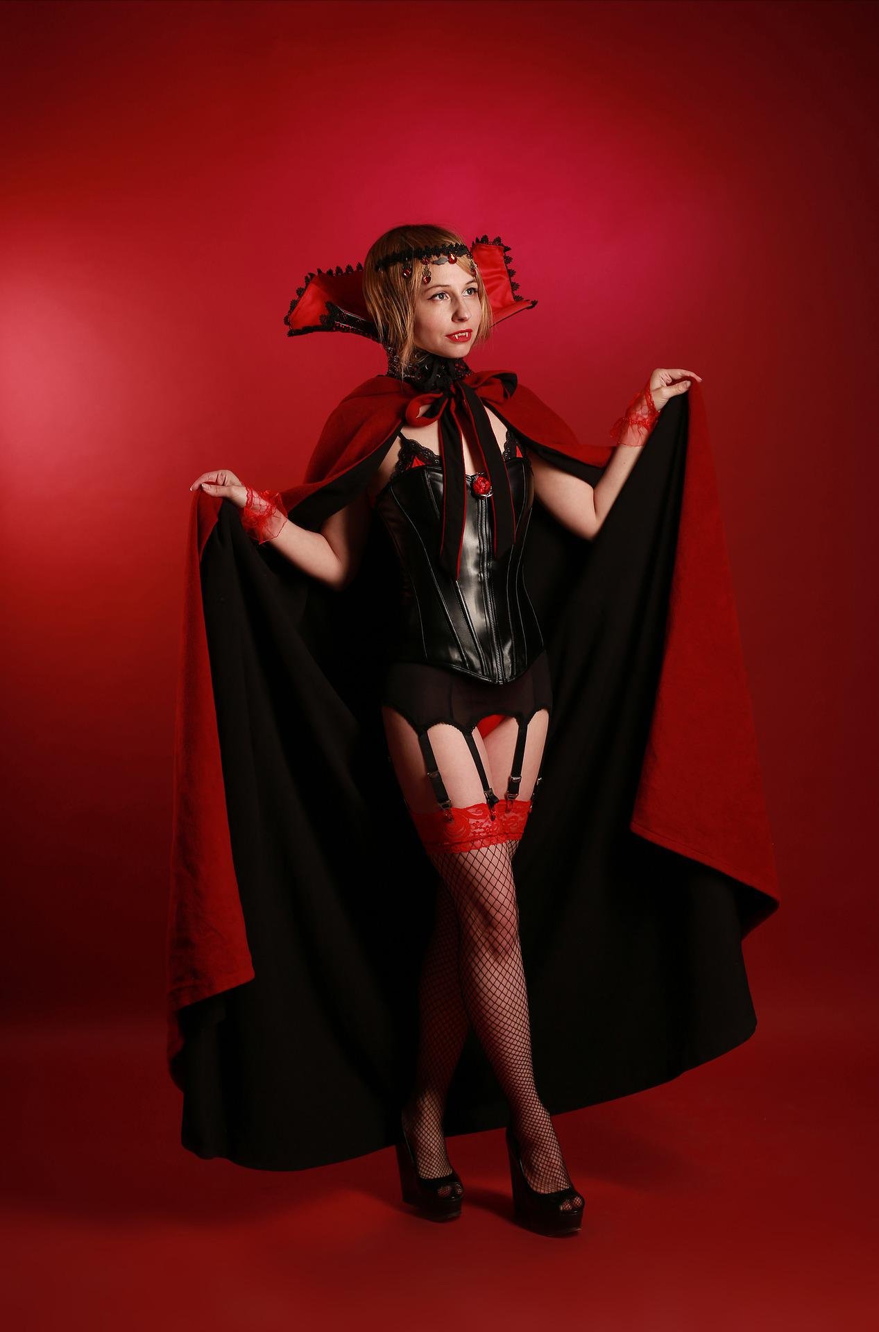 Gothic woman in dramatic jewelry and lace, striking a regal and mysterious pose with a shadowy backdrop.