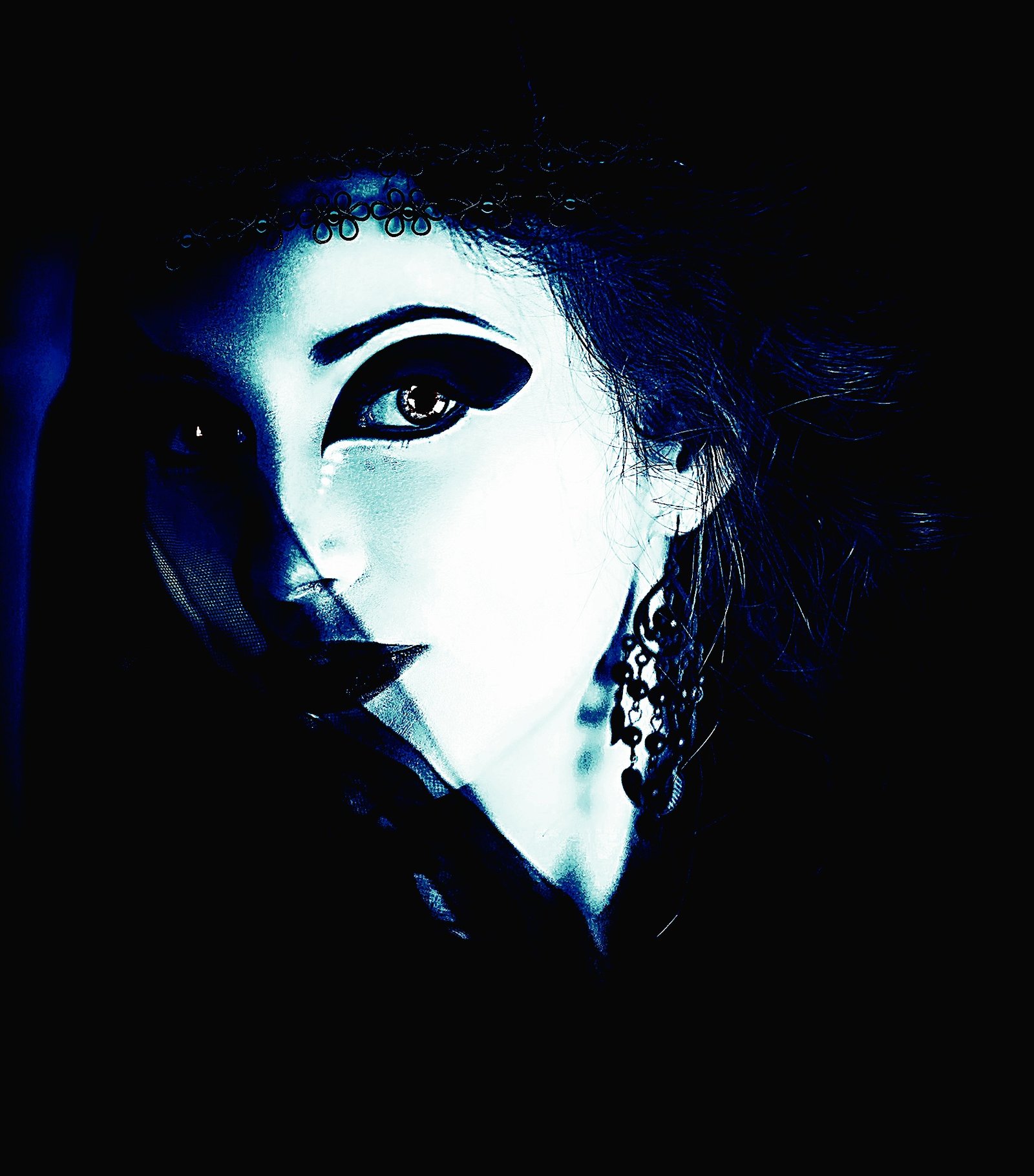 Stylized gothic portrait of a woman with exaggerated black eyeliner and a mysterious expression, captured in high contrast.