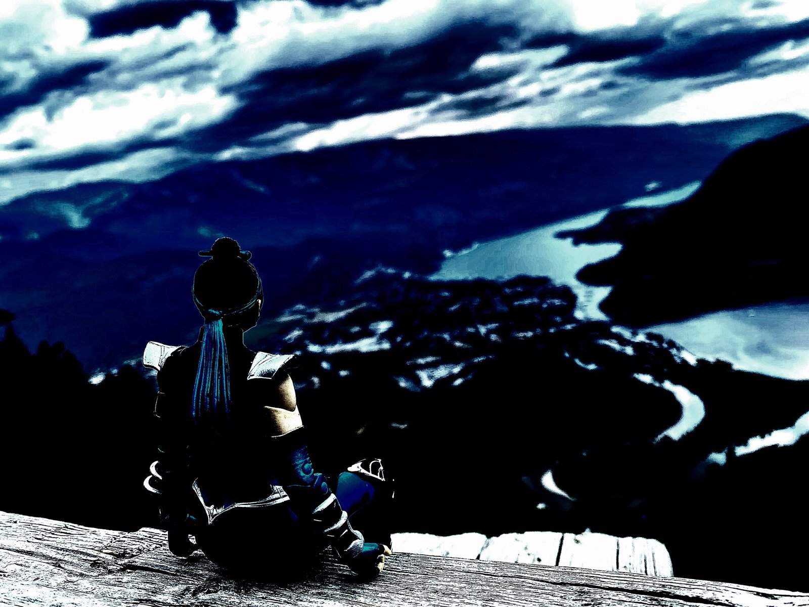 Cosplayer dressed as a fantasy warrior sitting on a wooden ledge overlooking a dramatic, stormy landscape.