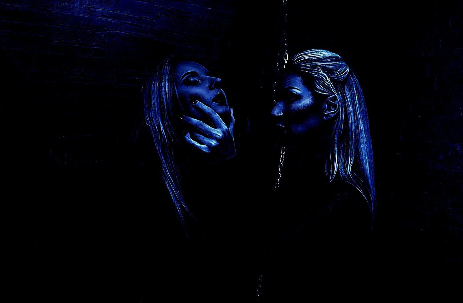 Woman in a dark room touching her own reflection, creating a surreal, intimate atmosphere.