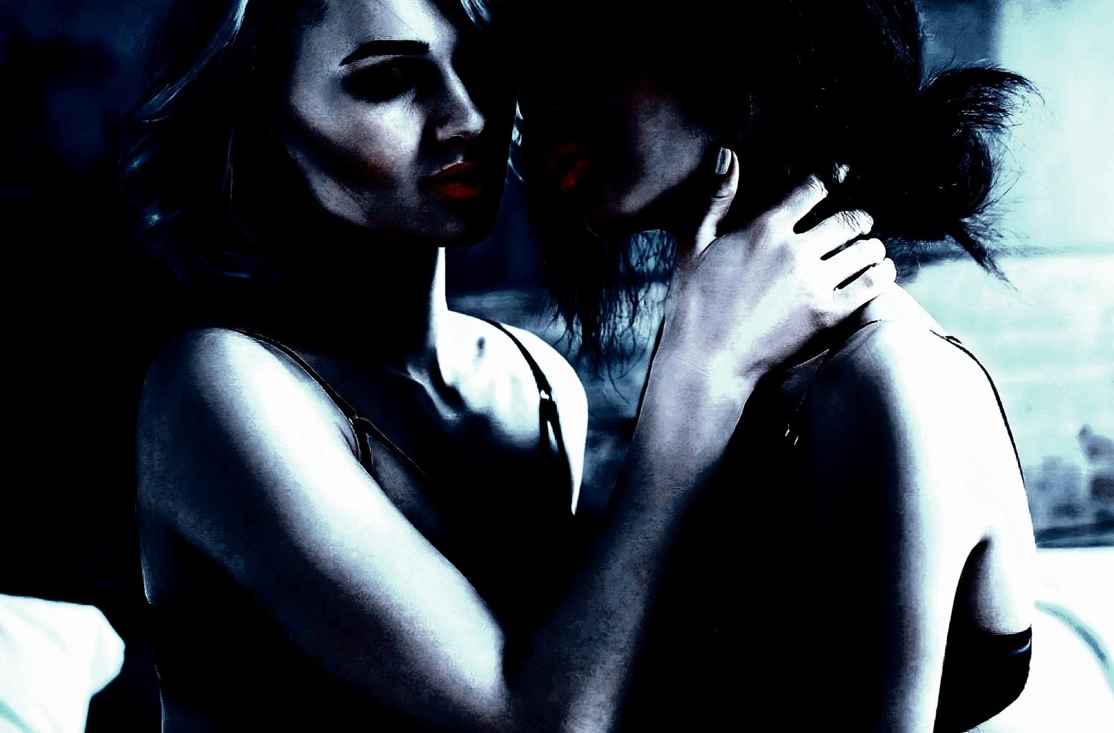 Two women sharing a sensual moment, one holding the other’s face with an intimate expression.
