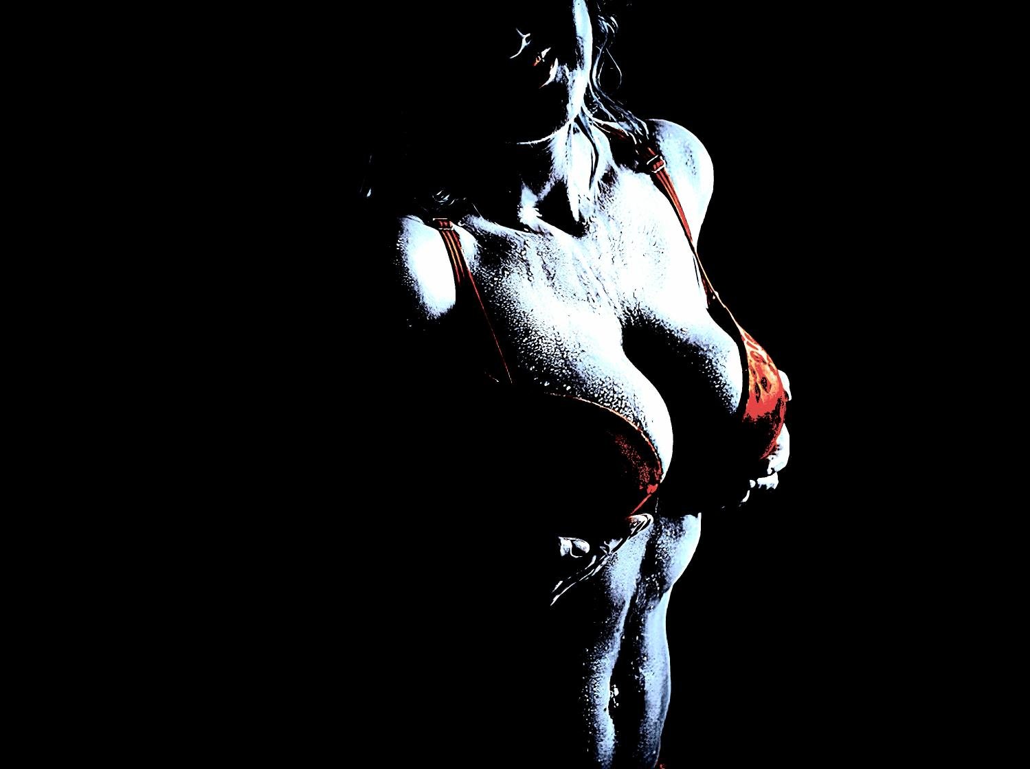 Woman in a red bra with water droplets glistening on her body, creating a powerful and sensual visual statement.