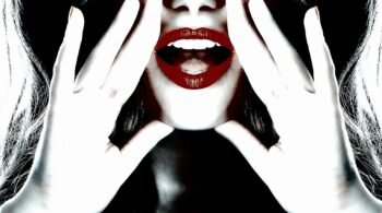 Close-up of a woman’s bright red lips and hands framing her face, creating a bold and striking look.