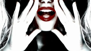 Close-up of a woman’s bright red lips and hands framing her face, creating a bold and striking look.