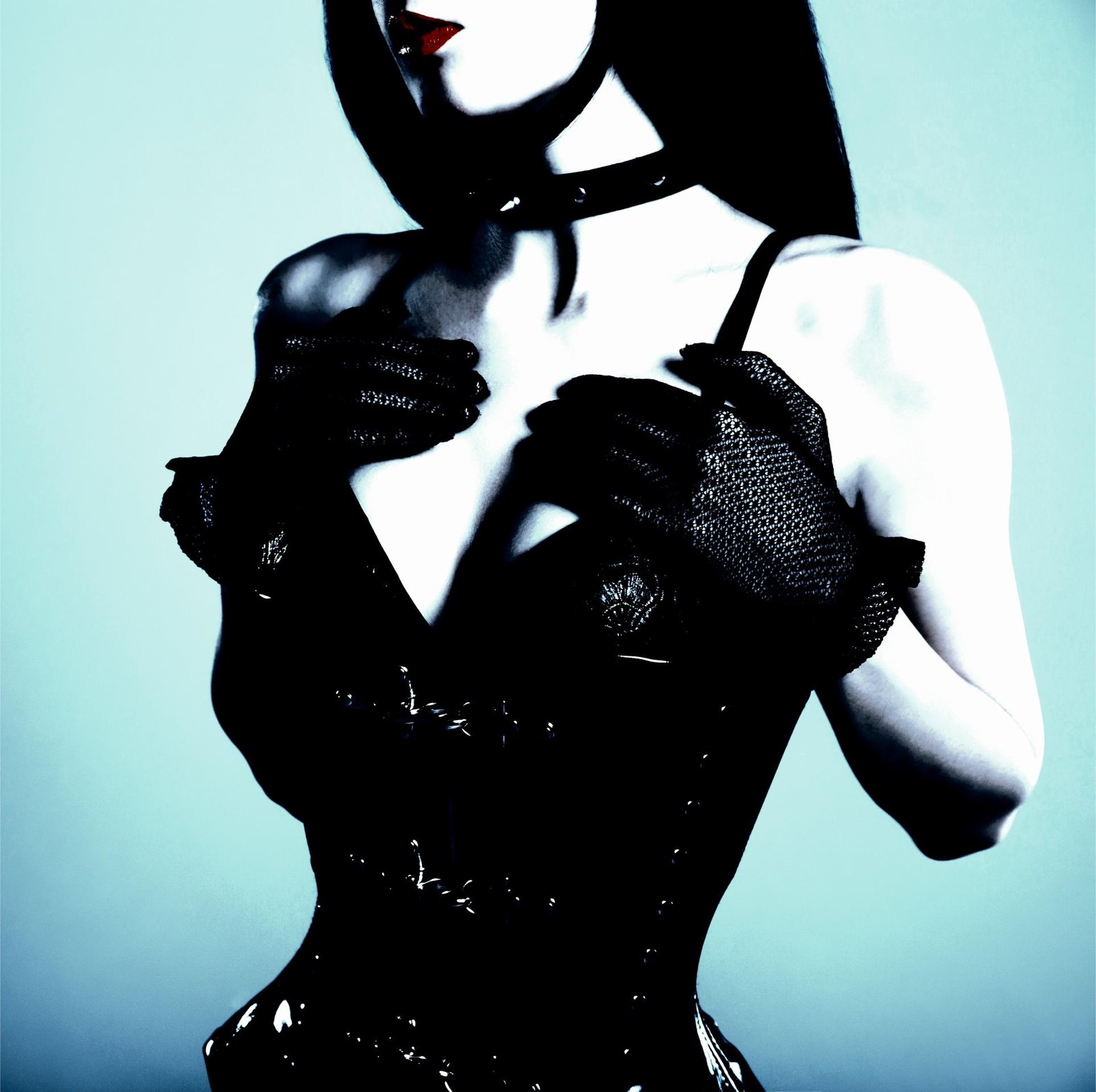 Close-up of a gothic model wearing a black corset with lace gloves, accessorized with a leather choker and red lipstick.