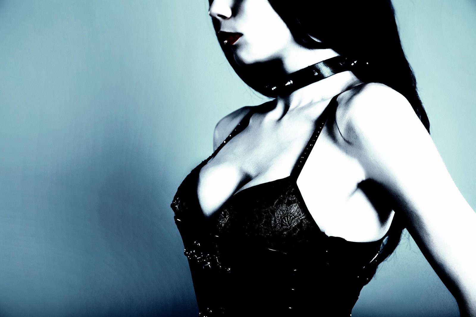 Close-up of a woman in a black corset with studded straps and a leather choker, highlighting gothic elegance.