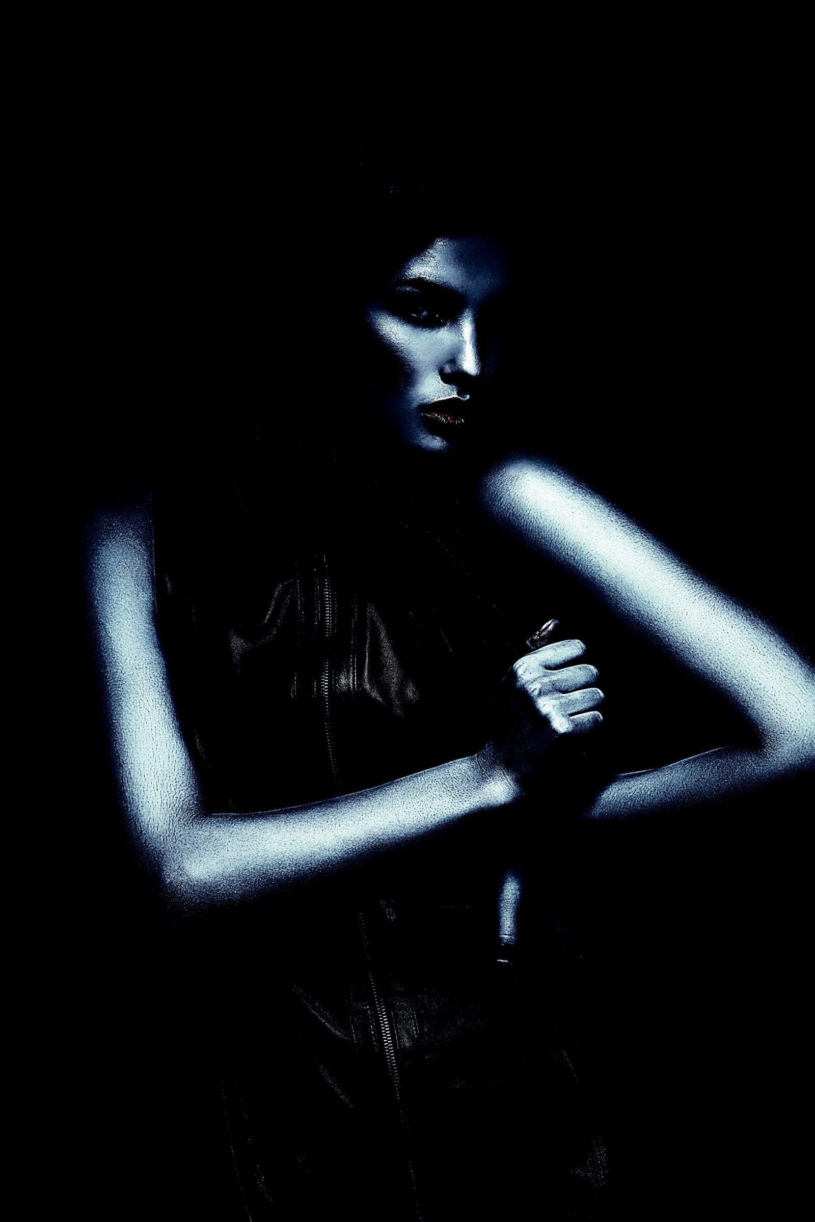 Mysterious gothic woman in a sleek black dress, shrouded in darkness, with a piercing, intense gaze.