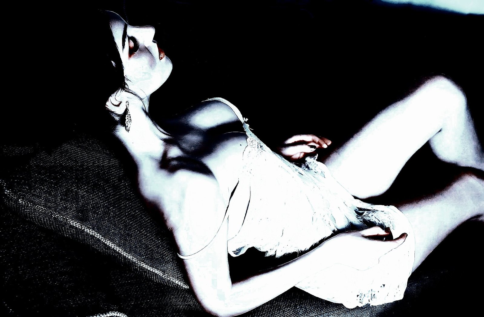 Reclining woman in a white lace dress, captured in soft lighting and a mysterious atmosphere.
