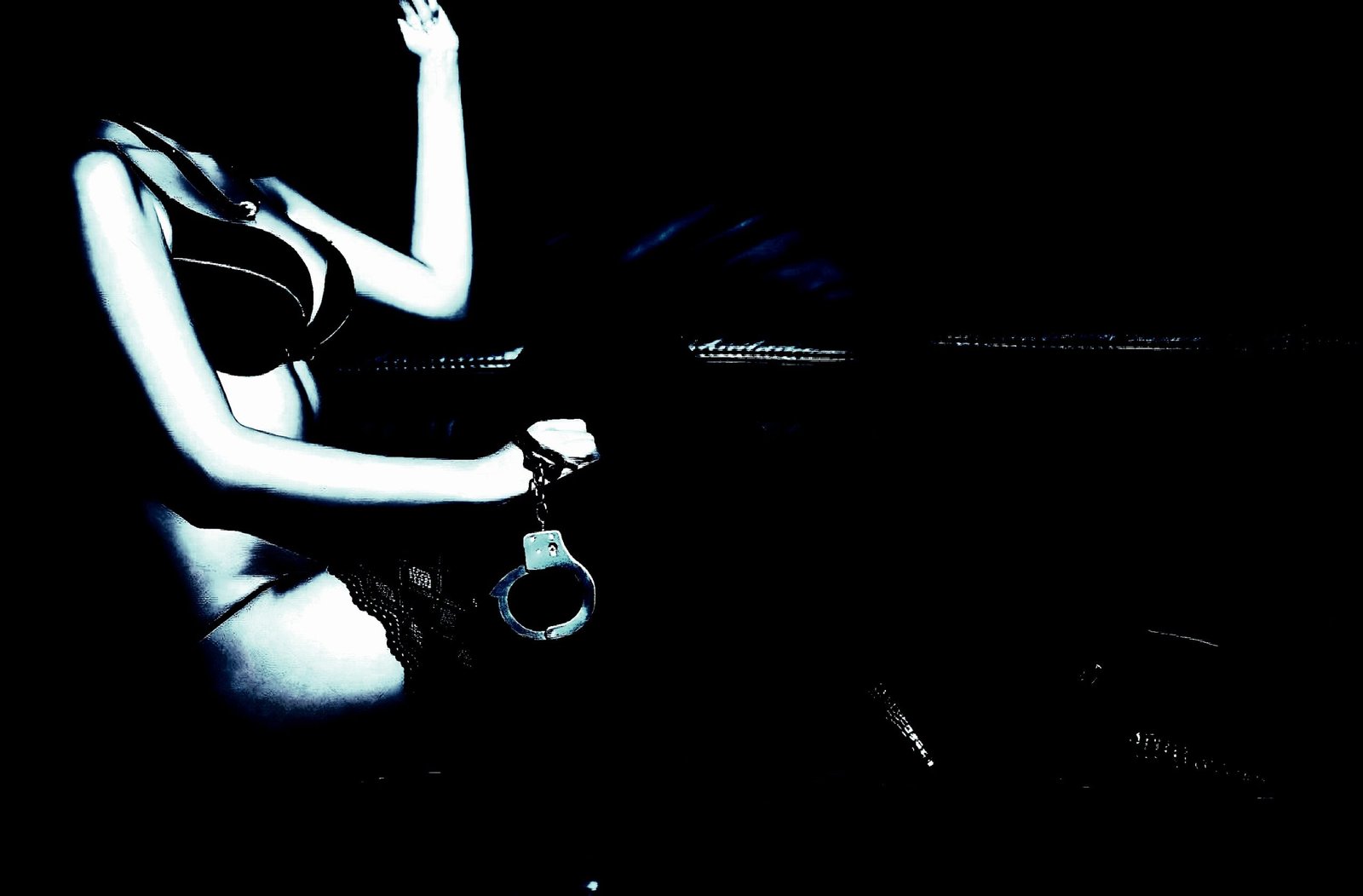 Woman in lingerie holding handcuffs, silhouetted dramatically against a dark background.