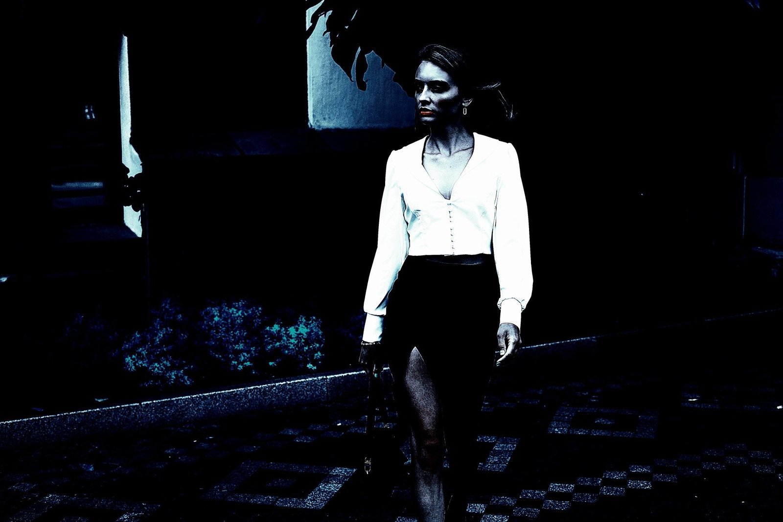  Elegantly dressed woman walking alone at night on a dimly lit pathway, exuding confidence and mystery.