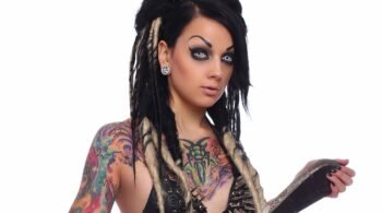Close-up of a gothic woman with striking white contact lenses, heavy black eyeliner, and a spiked leather bralette.