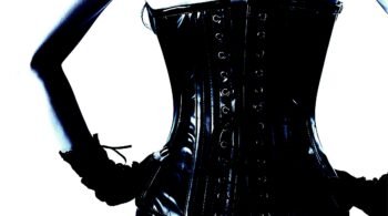 Close-up of a woman's back in a glossy black corset, accentuating an hourglass silhouette.