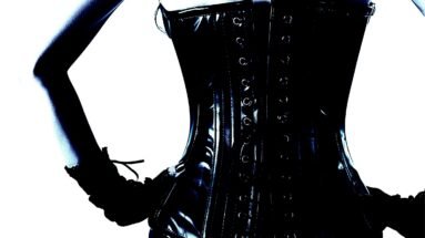 Close-up of a woman's back in a glossy black corset, accentuating an hourglass silhouette.
