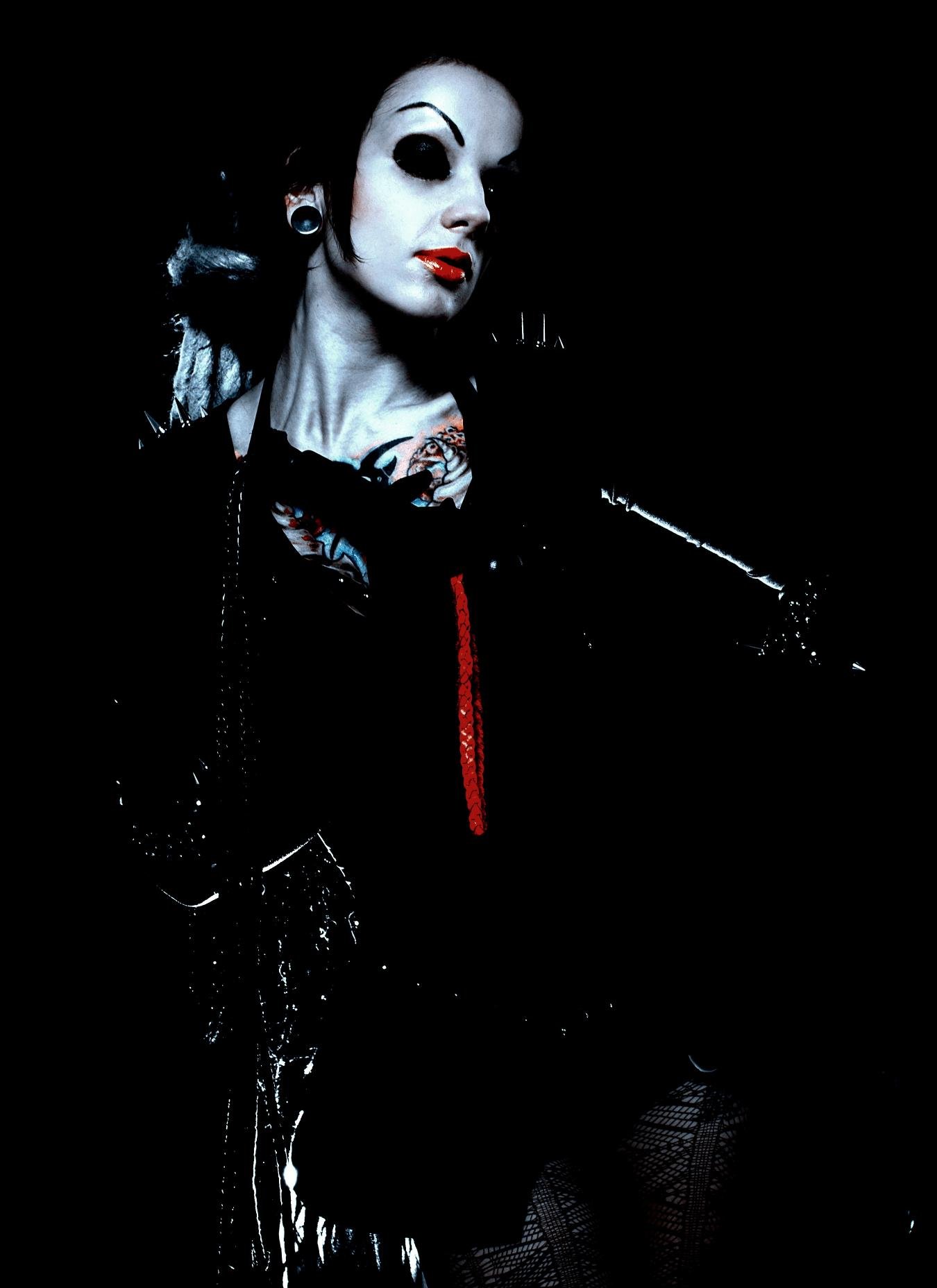 Gothic woman with dark makeup, tattoos, and a black corset, exuding a fierce and rebellious aura.