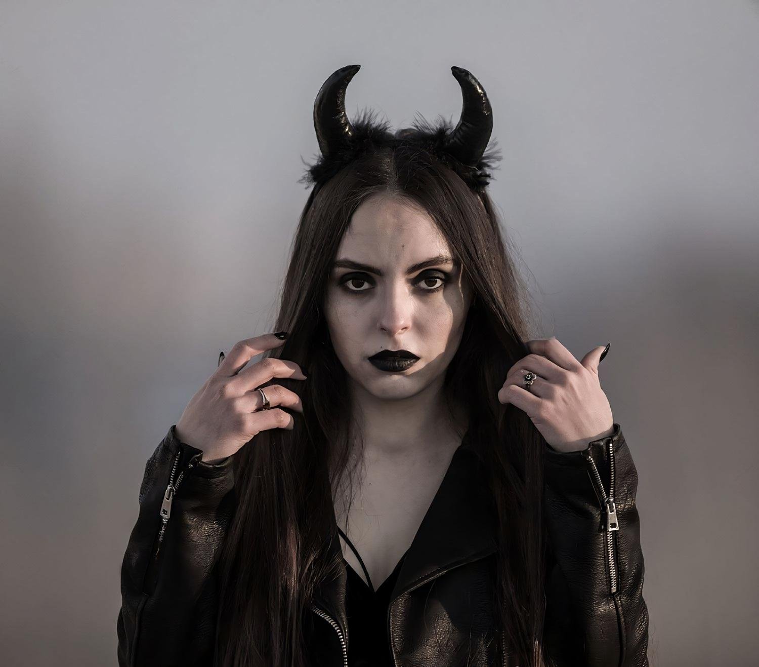 Gothic woman with devil horns, black lipstick, and leather jacket in moody lighting