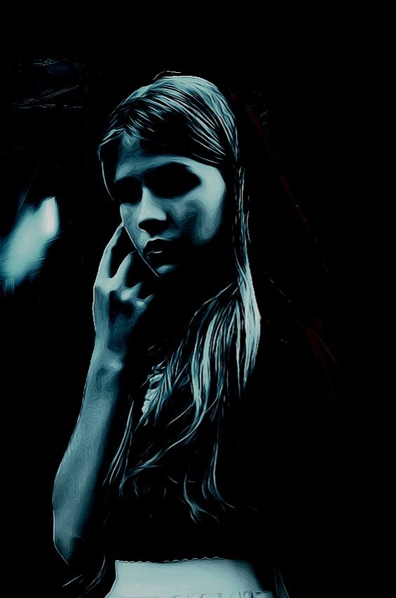 Mysterious young woman with long hair in a dark setting, touching her face, exuding gothic melancholy.