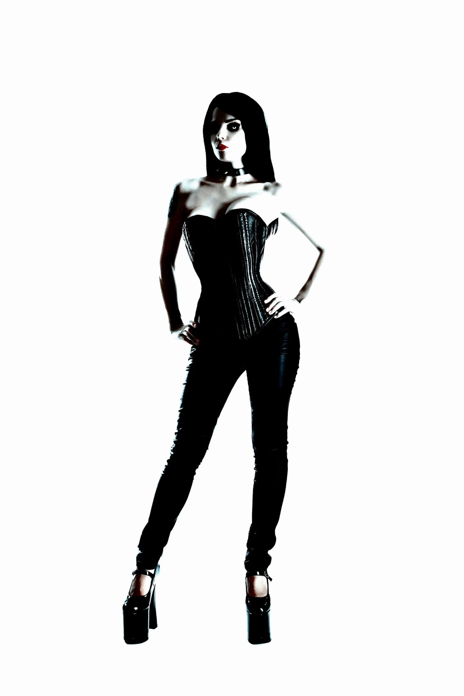 A goth model in a black corset and high heels, standing confidently against a stark white background.