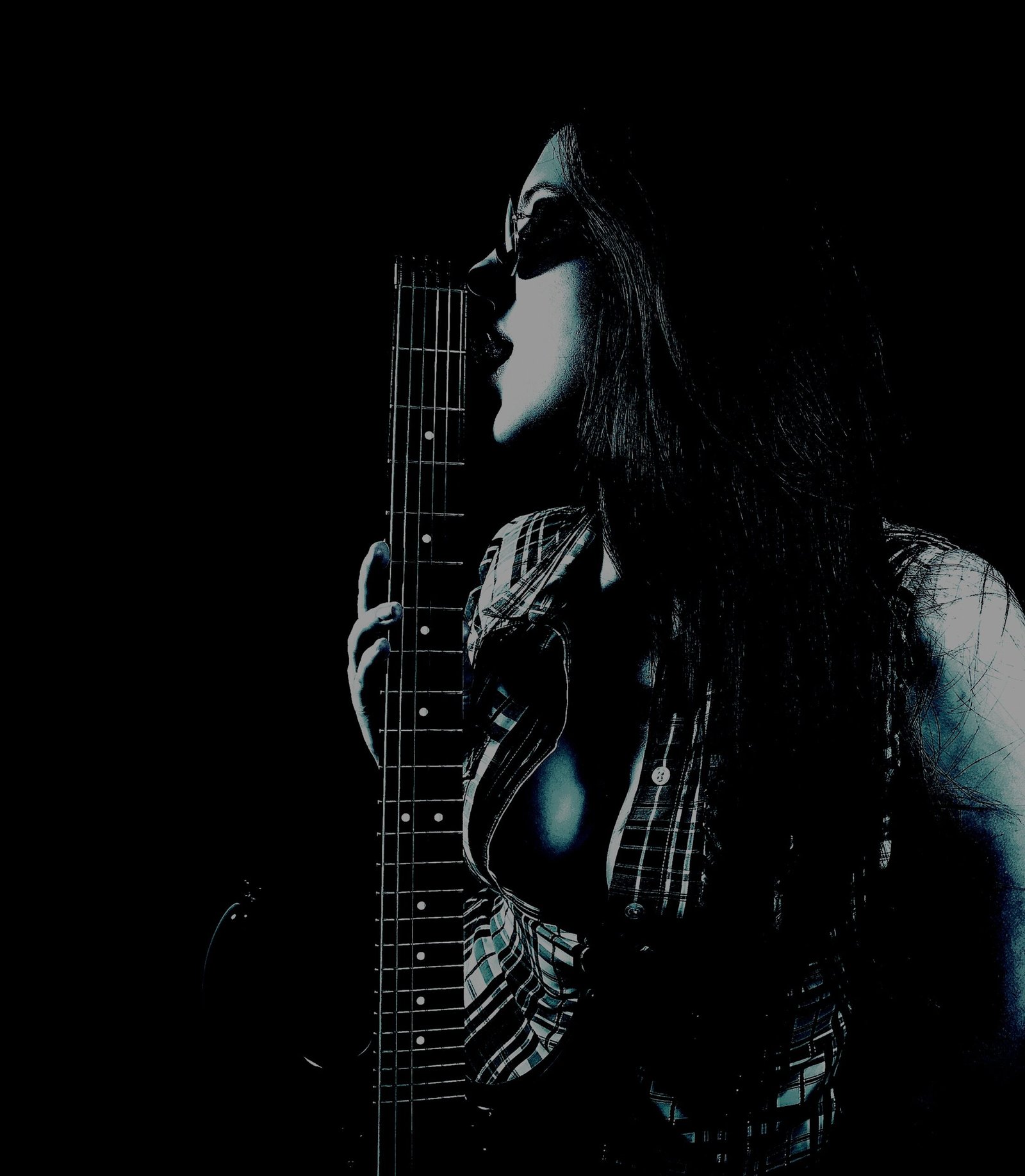 Woman holding a guitar, leaning against it seductively in a shadowy setting with plaid clothing details.