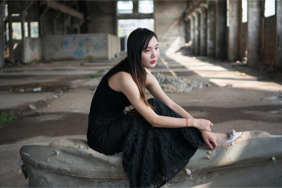 Woman in long black lace gothic skirt sitting in abandoned industrial building